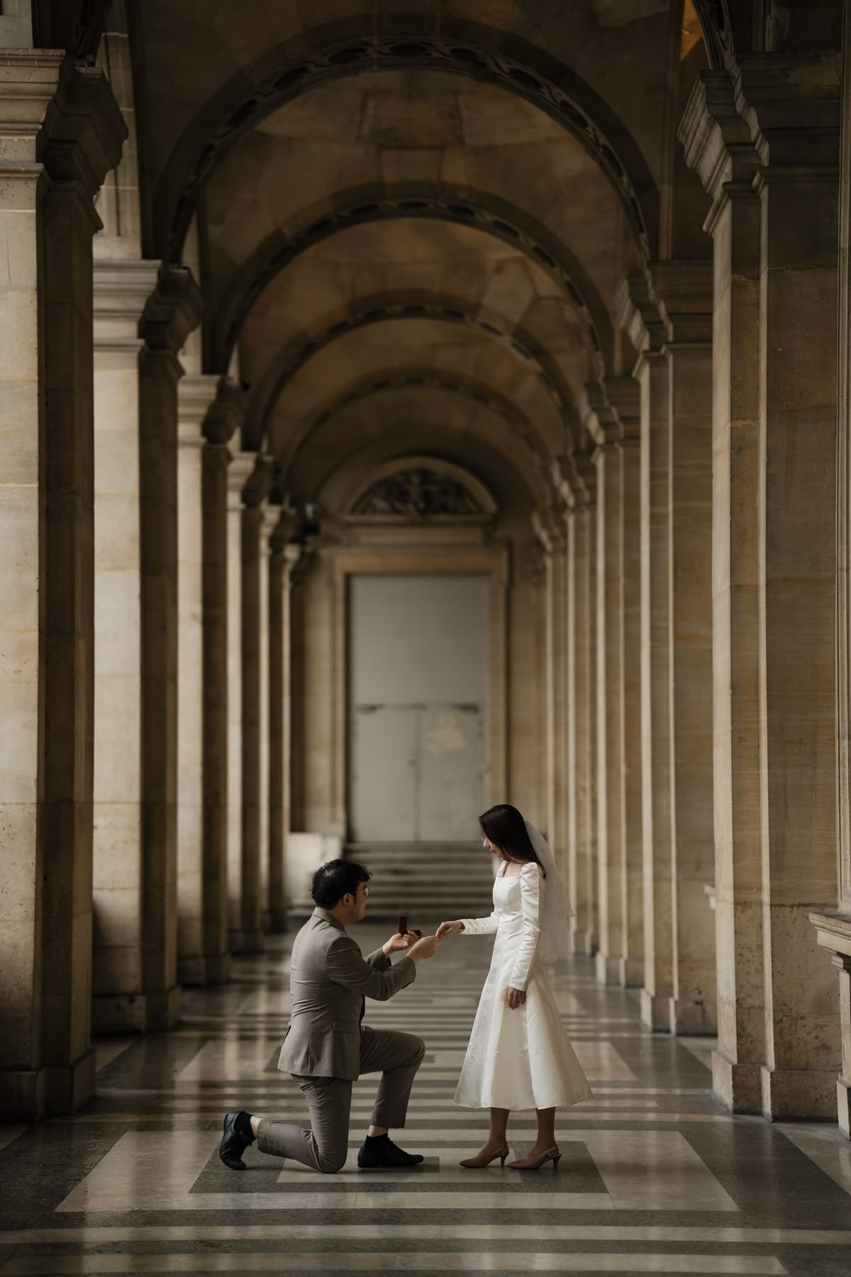 Bride and groom under Parisian columns during an elegant elopement photoshoot