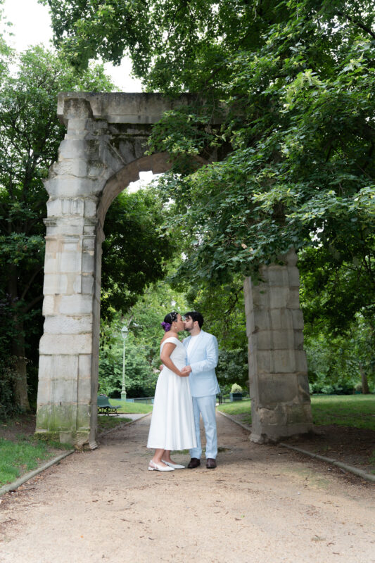 Bride and groom kissing under the stone arch in Parc Monceau Paris