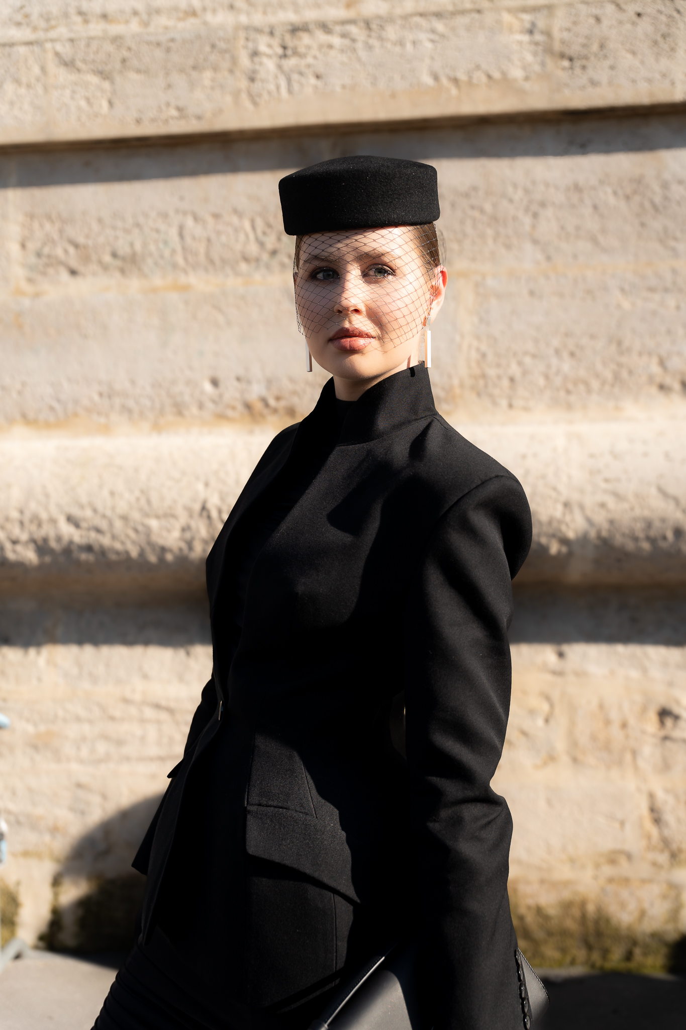 Close portrait of a client in a structured black outfit during Paris Fashion Week
