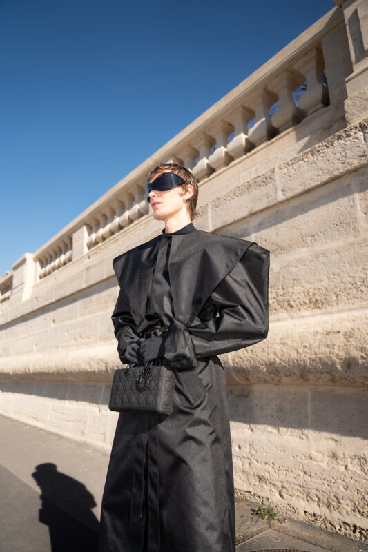 Full fashion portrait of a client wearing a structured black outfit during Paris Fashion Week