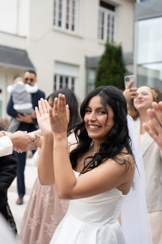 Bride clapping with guests outside L’Haÿ-les-Roses City Hall after her wedding