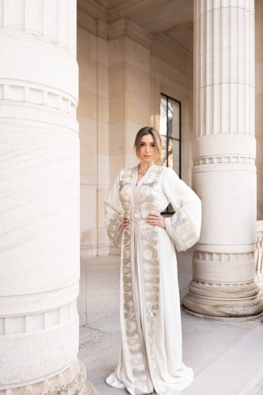 Woman in an embroidered caftan posing by a column near Palais de Tokyo in Paris