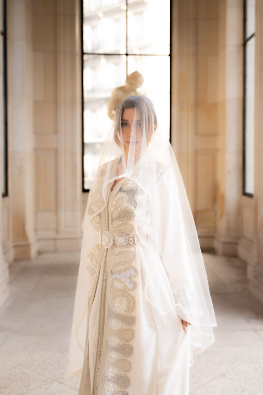 Woman wearing a veil and embroidered caftan in an editorial shoot near Palais de Tokyo in Paris