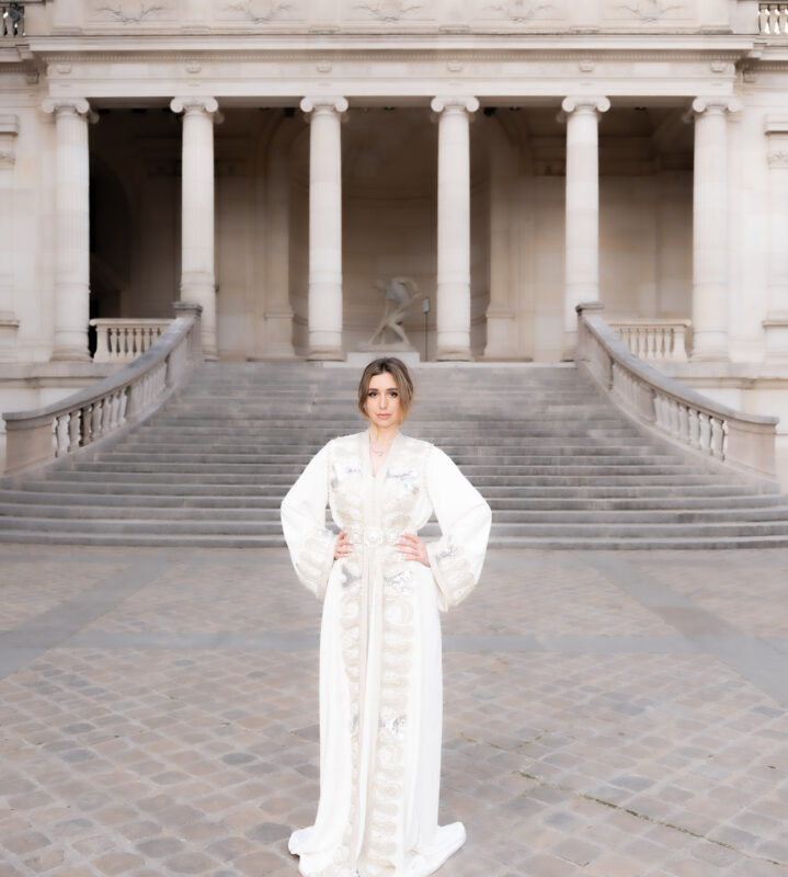 Editorial portrait of a woman in an embroidered caftan on the steps near Palais de Tokyo in Paris