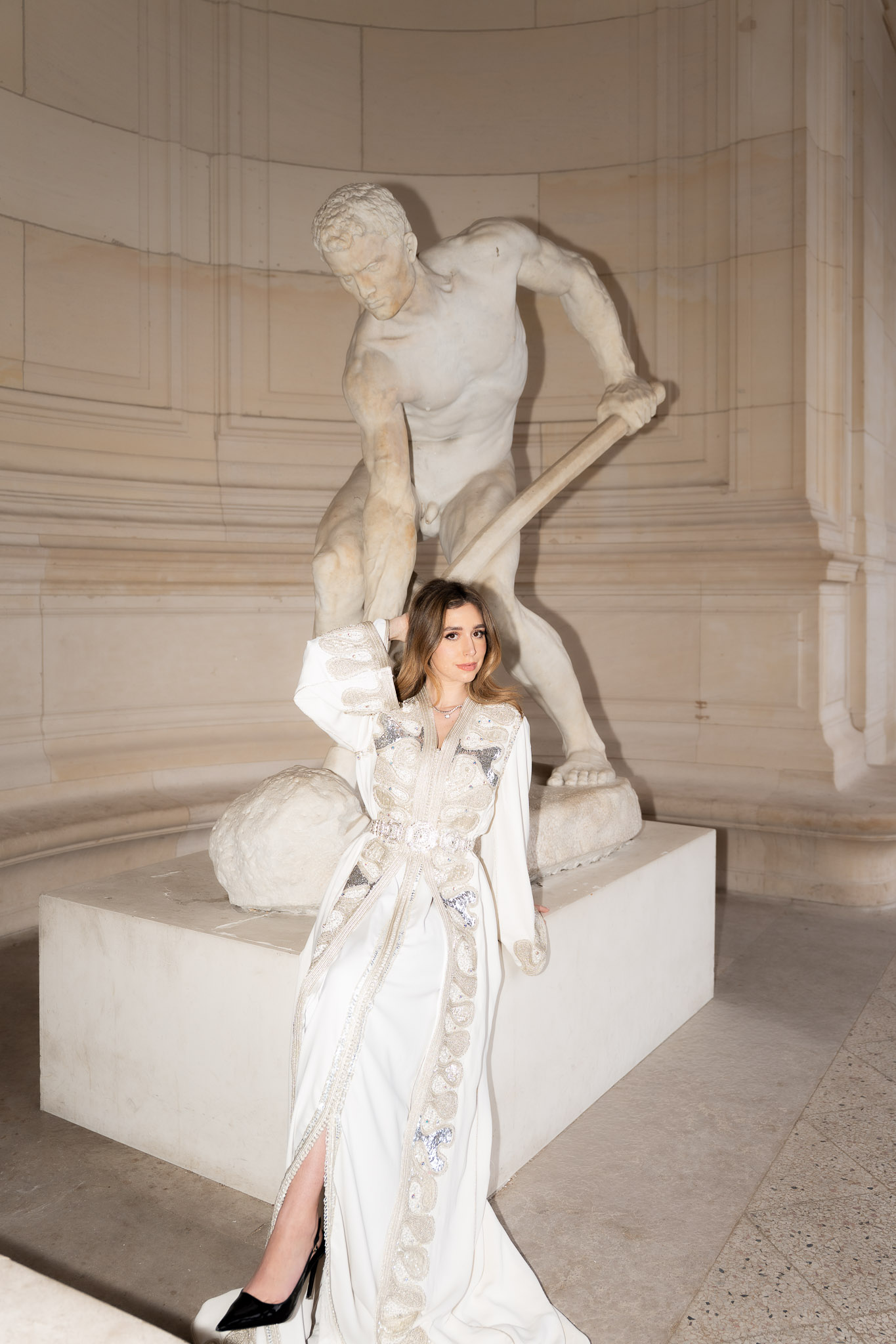 Woman standing near a sculpture in an embroidered caftan during a Paris editorial shoot