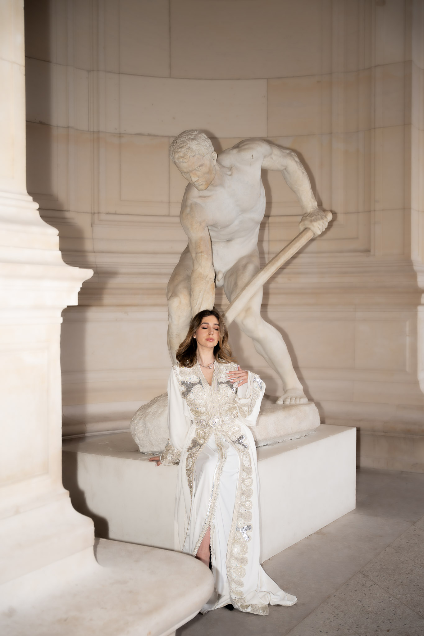 Full-length editorial portrait of a woman in a caftan near a sculpture in Paris
