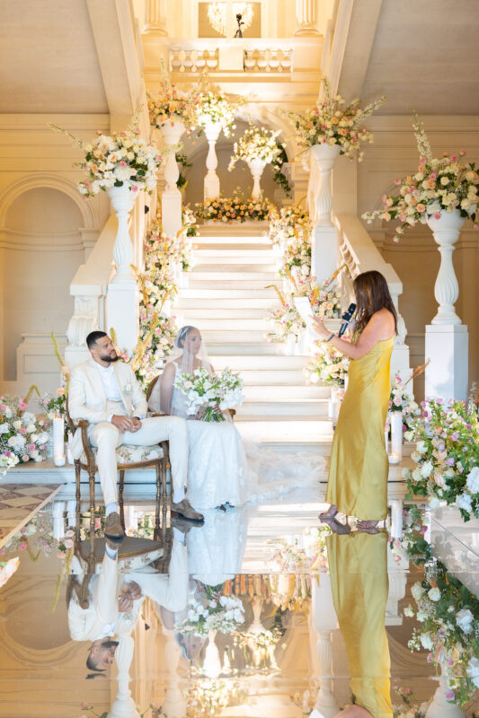 Bride and groom seated beneath floral ceremony décor at Château de Saint-Martin-du-Tertre
