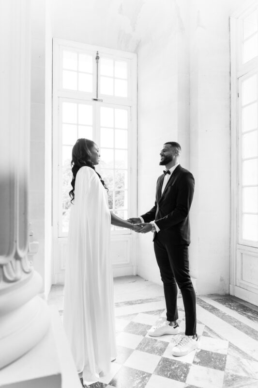 Black-and-white portrait of the bride and groom by the window at Château de Saint-Martin-du-Tertre