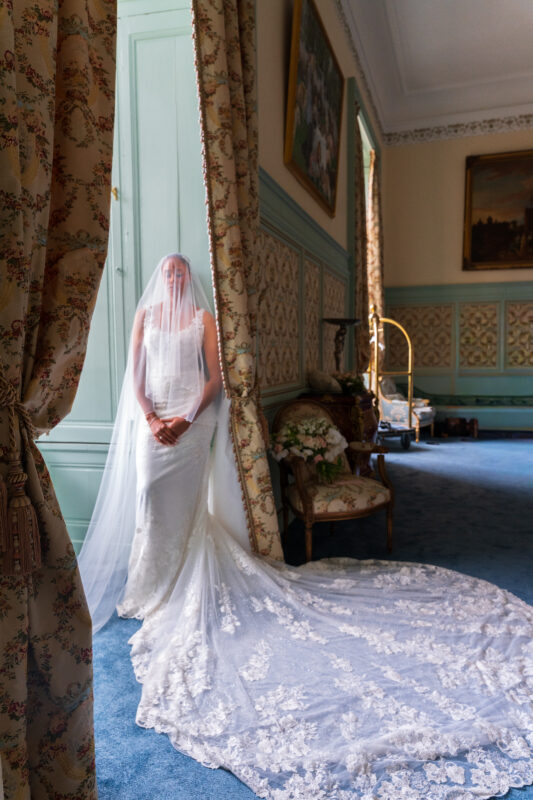 Bride standing in an elegant room wearing her veil at Château de Saint-Martin-du-Tertre