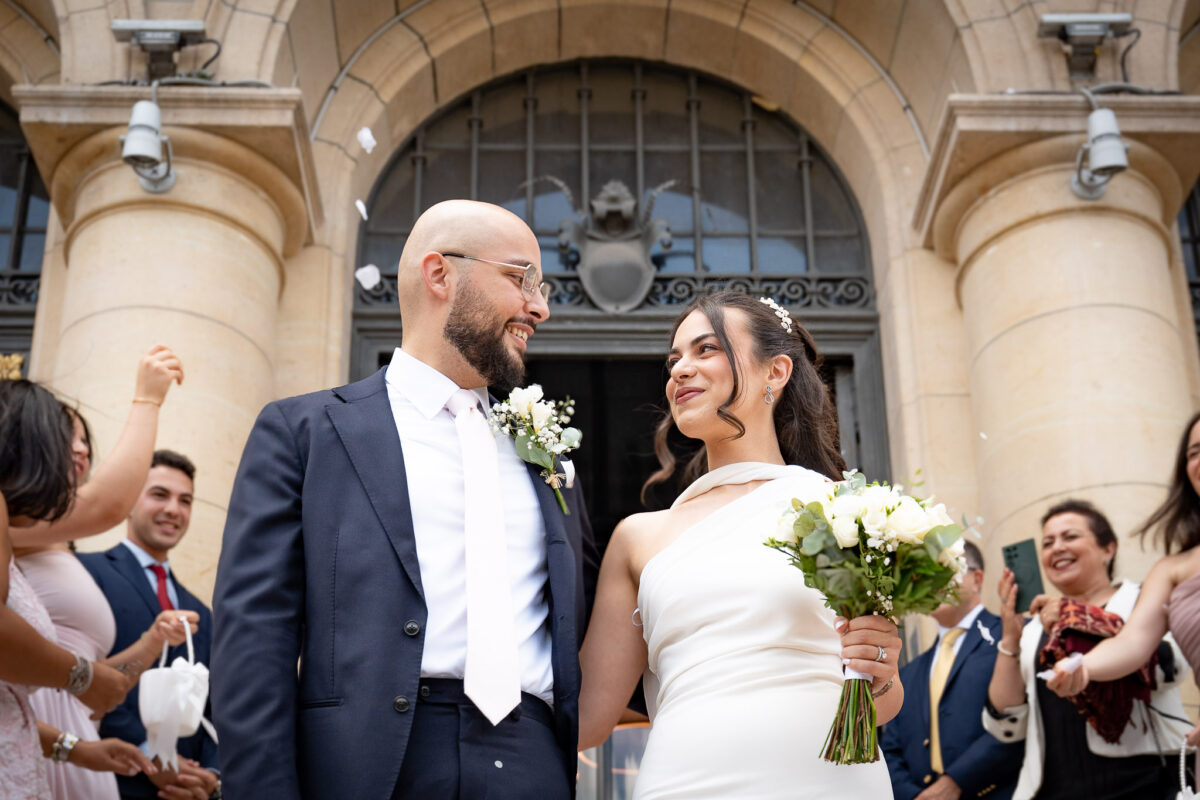 Bride and groom outside Suresnes City Hall beneath an arched entrance