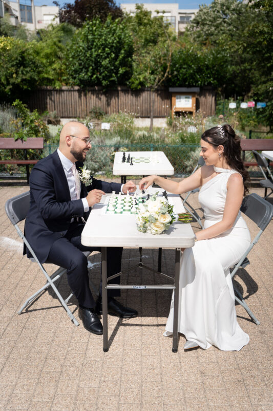 Bride and groom sitting at a table with a chessboard after their civil wedding in Suresnes