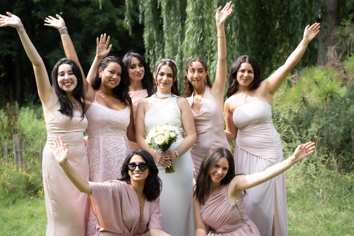 Bride and bridesmaids celebrating together in a garden after the wedding ceremony