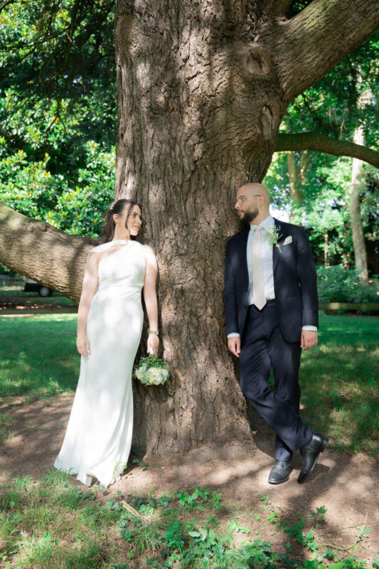 Bride and groom standing under a tree during their wedding portraits in Île-de-France