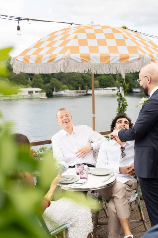 Groom speaking during an outdoor wedding reception by the river near Paris