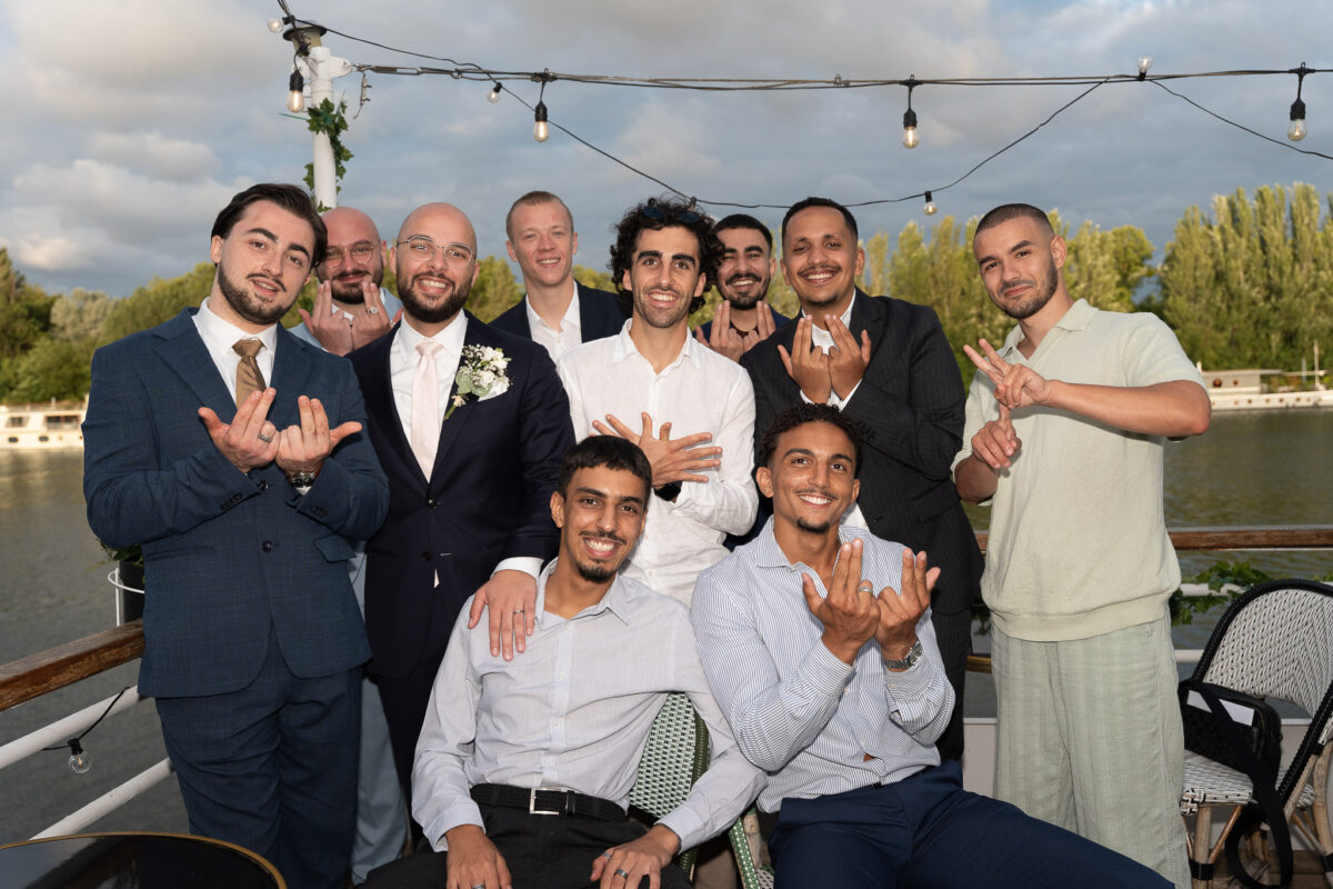 Groom posing with friends during a wedding celebration by the river in Île-de-France