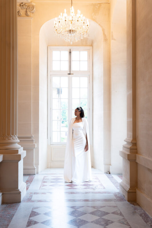 Bride standing in an elegant hallway at Château de Saint-Martin-du-Tertre